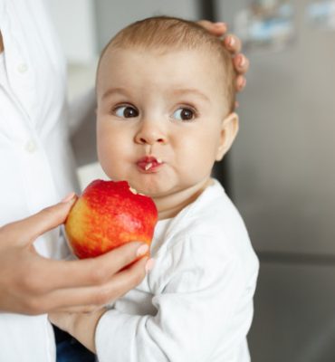 foto-recortada-da-mae-dando-uma-fatia-de-maca-ao-bebe_176420-19779